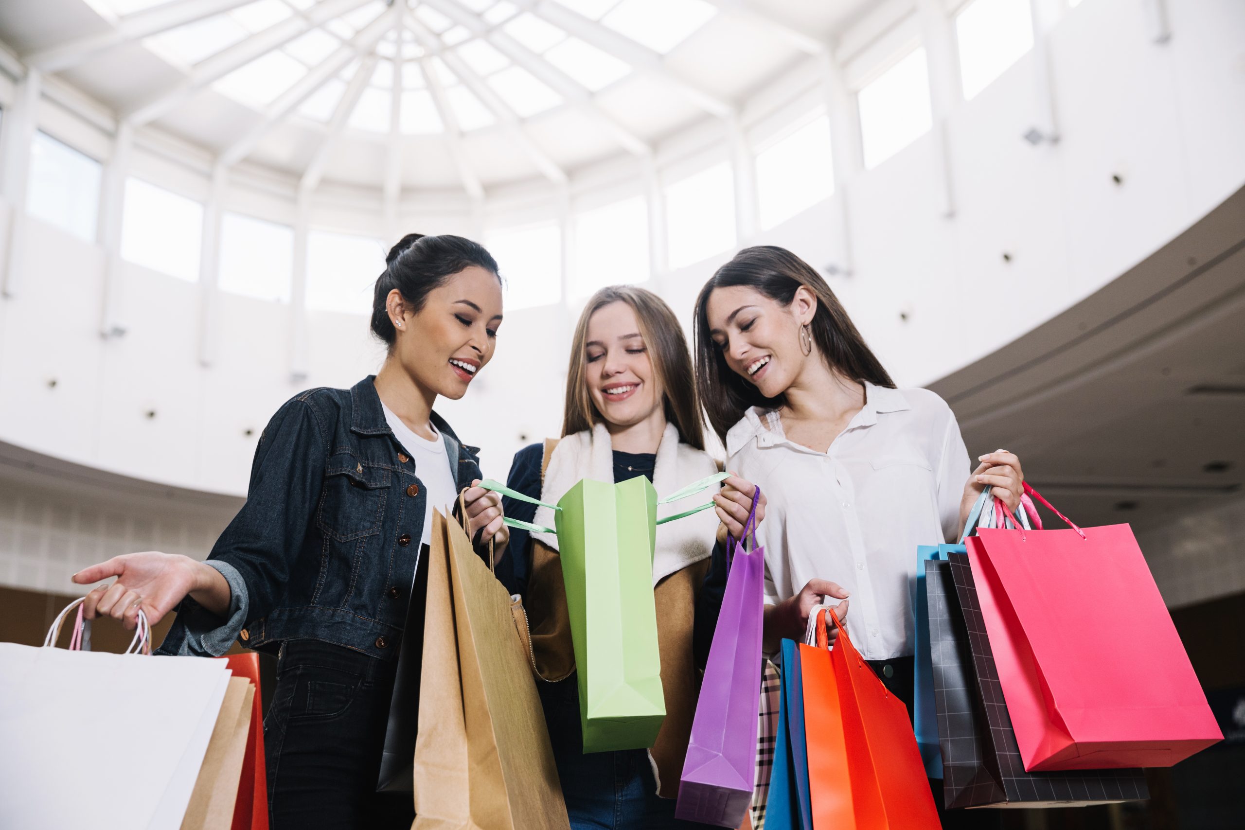 girls holding colorful shopping bags in a mall