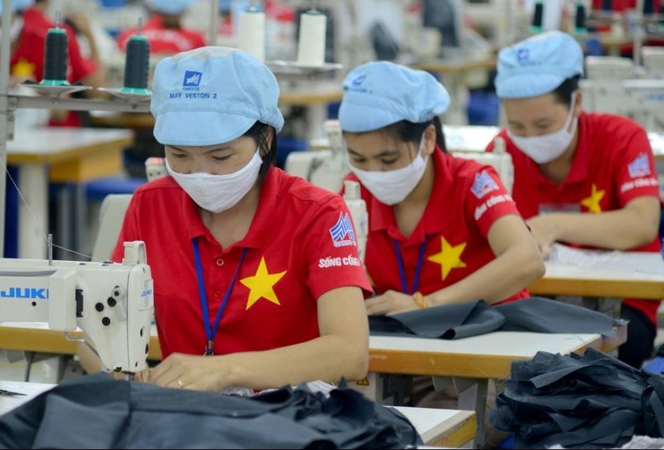 three garment workers are sewing clothes in a Vietnamese factory